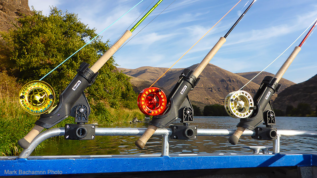 Threes Spey outfits in a jet boat rod rack, with the Deschutes River in the background.